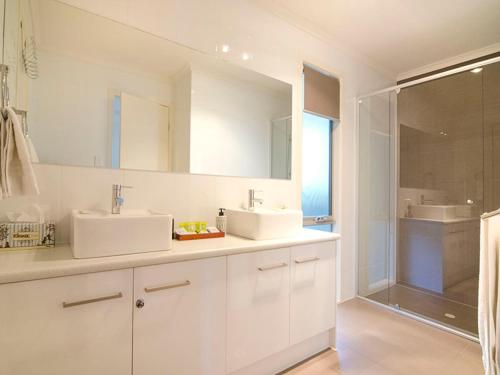 a white bathroom with two sinks and a shower at Seagrass Villas Normanville in Normanville