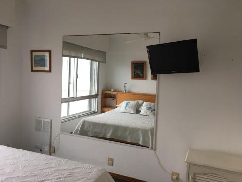 a mirror in a bedroom with a bed and a television at Departamento Vista al Mar in Punta del Este