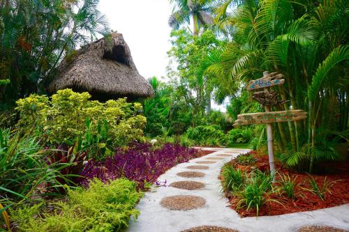a walkway in a tropical garden with a sign at Riverside by the Beach Apartments in Pompano Beach