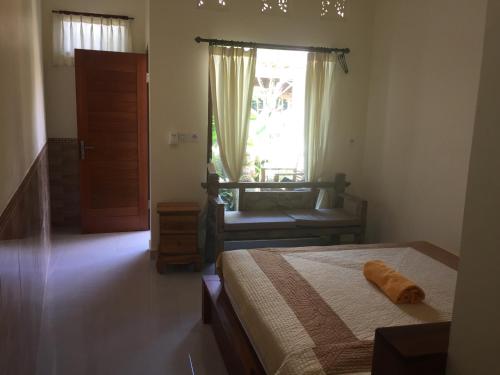 um quarto com uma cama, uma janela e uma cadeira em Blima Bali em Ubud