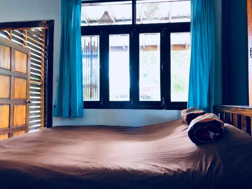 a bedroom with a large bed with blue curtains at JJ at Chiangkhan in Chiang Khan