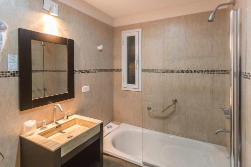een badkamer met een bad, een wastafel en een spiegel bij Hotel Las Maras in Puerto Madryn