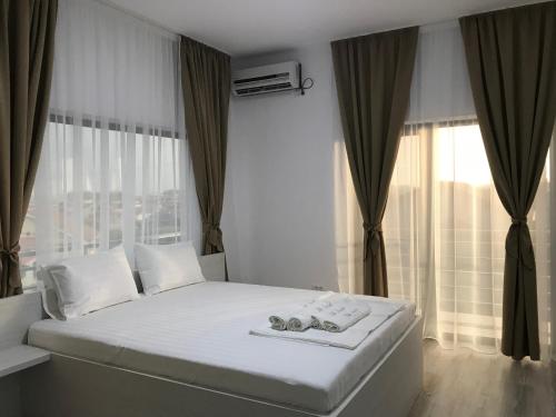 a bedroom with a white bed with a large window at Casa Decebal in Eforie Nord