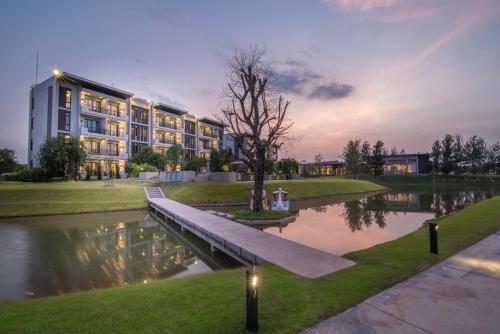 a building with a bridge next to a pond at Green Ville Laguna Hotel in Sung Noen