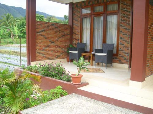 a house with a patio with chairs and a table at Toba Village Inn in Tuk Tuk