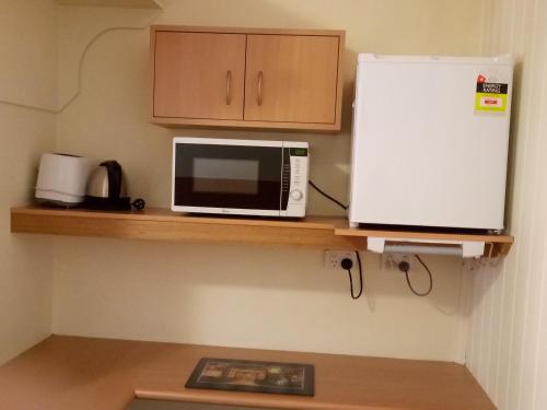a microwave and a refrigerator on a wooden shelf at Clifton Motel in Albury