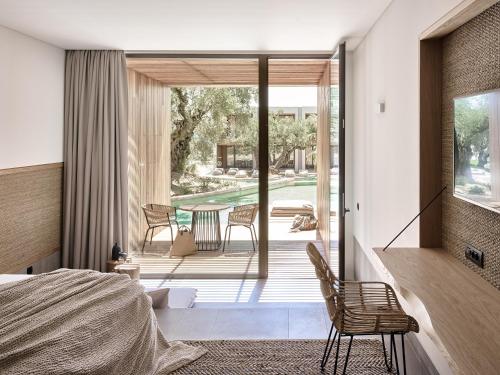 a bedroom with a bed and a patio with a table at Olea All Suite Hotel in Tsilivi