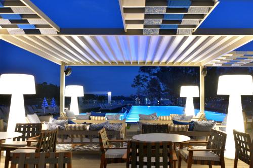 a patio with tables and chairs and a pool at night at Rodostamo Hotel & Spa- Adults Friendly in Kommeno