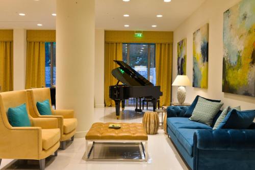 a living room with a blue couch and a piano at Rodostamo Hotel & Spa- Adults Friendly in Kommeno