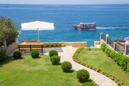 a bench with an umbrella and a boat in the water at Apartments Piano in Utjeha