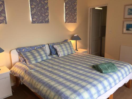 a bedroom with a bed with a blue and white checkered blanket at Breede View Holiday Home in Witsand