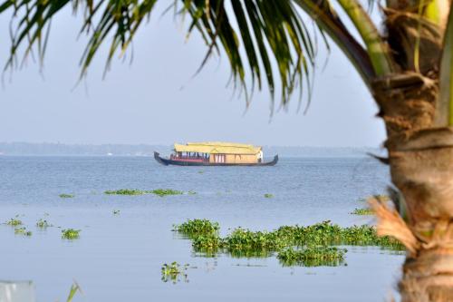 a boat on the water with a palm tree at Marari Bethsaida Homestay in Shertallai