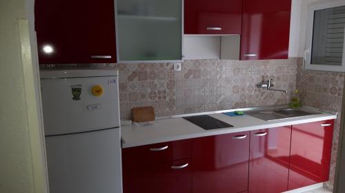 a kitchen with red cabinets and a white refrigerator at Apartments Babić in Novalja