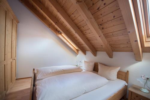 a bed in a room with a wooden ceiling at Ferienwohnung Fauser in Oberstdorf