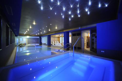 ein großer Pool in einem Gebäude mit blauen Lichtern in der Unterkunft Family Hotel Andes - Only for Family in Vigo di Fassa