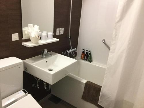 a bathroom with a sink and a toilet and a shower at Maebashi Business Hotel Luka in Maebashi