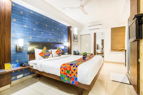 a bedroom with a large bed with a blue wall at FabExpress Kalyan in Vadodara