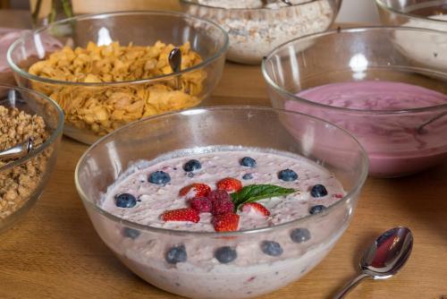 a table topped with bowls of yogurt and berries at Berghotel Chäserstatt in Ernen