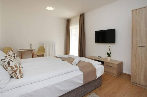 a bedroom with a bed and a tv on the wall at Boutique Apartments in Hévíz