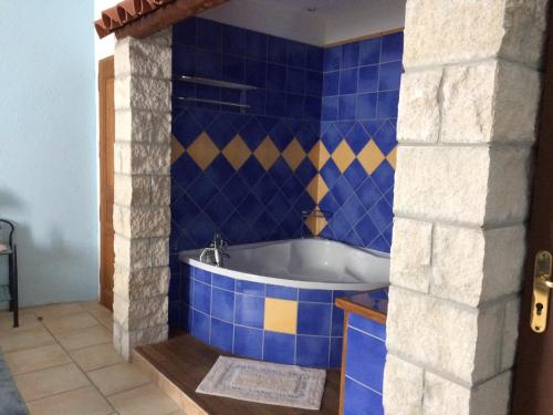 a bath tub in a blue tiled bathroom at La Mais'Ange in Berrias Et Casteljau