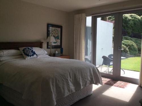 a bedroom with a bed and a sliding glass door at Hadley Close in Dunedin