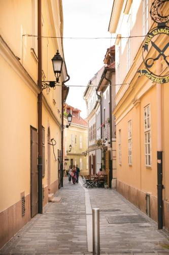 an alley in an old town with people walking down it at Főtér Rezidencia in Győr