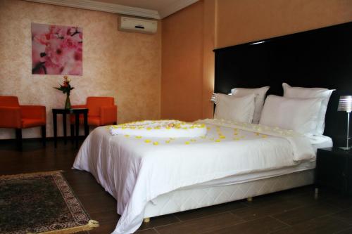 Un dormitorio con una gran cama blanca con flores amarillas. en Ubay Hotel, en Rabat