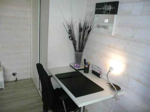 białe biurko z krzesłem i wazonem z patyków w obiekcie Studio BORDEAUX ST AUGUSTIN w mieście Bordeaux