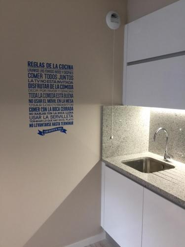 uma cozinha com um lavatório e uma placa na parede em Port Bidassoa - T2 Coquet, Parking, Lit XXL, wifi, près de la gare em Hendaye
