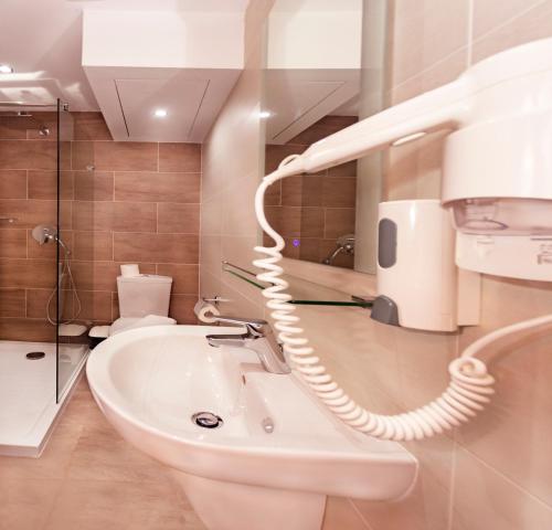 a bathroom with a white sink and a hair dryer at Cerviola Hotel in Marsaskala