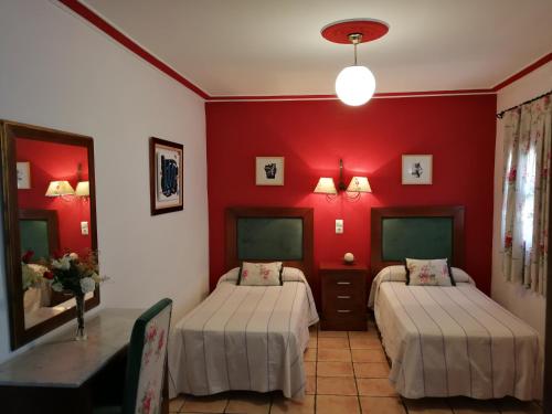 2 camas en una habitación con paredes rojas en Hostal Maestre en Córdoba