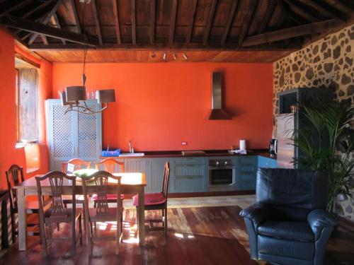 a kitchen with orange walls and a table and chairs at Haciendas del Valle - Las Kentias in Valle de Guerra