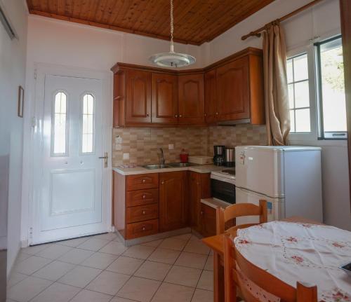 a kitchen with wooden cabinets and a white refrigerator at Fotini's Apartments - Pelekas Beach in Pelekas