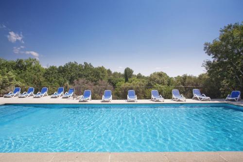 a group of chairs sitting next to a swimming pool at Résidence Odalys La Bastide des Chênes in Gordes