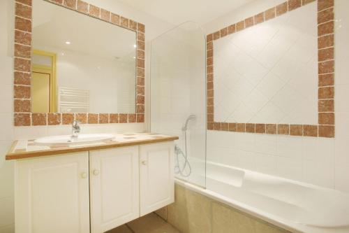 a bathroom with a sink and a tub and a mirror at Résidence Prestige Odalys La Bastide des Chênes in Gordes