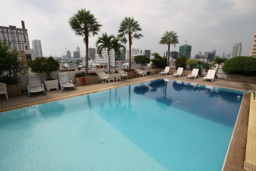 a large swimming pool with chairs and palm trees at Baiyoke Suite Hotel in Bangkok