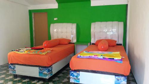 2 Betten in einem Zimmer mit Grün und Orange in der Unterkunft AAL Homestay in Sabang