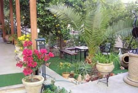 a garden with flowers and tables and a pond at Villa Manolis in Tolo