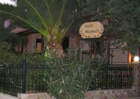 a restaurant with a sign in front of a fence at Villa Manolis in Tolo