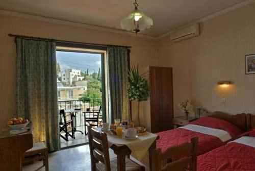 a bedroom with a bed and a table and a window at Villa Manolis in Tolo