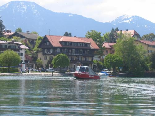 a boat in the water in front of buildings at Seehotel Luitpold in Tegernsee
