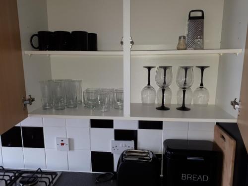 a shelf with glasses and wine glasses on it in a kitchen at Seabreeze in Littlestone-on-Sea