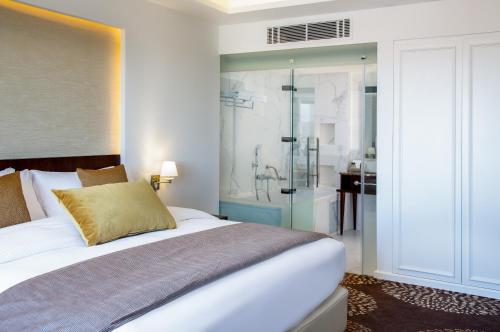 a bedroom with a large bed and a shower at Mövenpick Hotel Amman in Amman