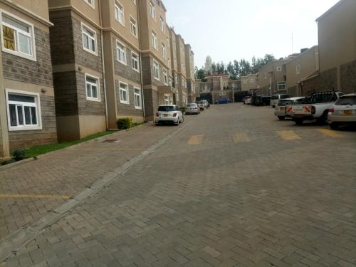 a parking lot with cars parked next to a building at Furnished Homes Nakuru with pool & GYM in Nakuru