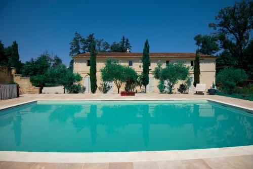 a large swimming pool in front of a house at La villa bella in Abzac