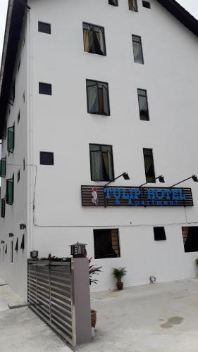 a white building with a blue sign on it at TULIP HOTEL & APARTMENT in Cameron Highlands