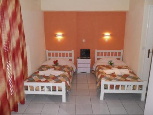 two beds in a room with orange walls at Villa Markos in Perissa