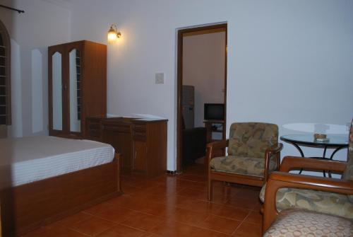 a bedroom with a bed and a chair and a table at Albuquerque BetterHomes, Goa in Candolim