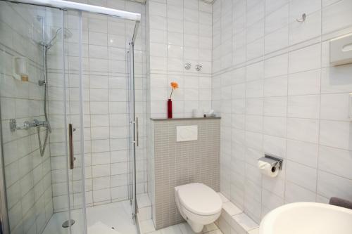 a white bathroom with a shower and a toilet at Hotel Berliner Ring in Bamberg