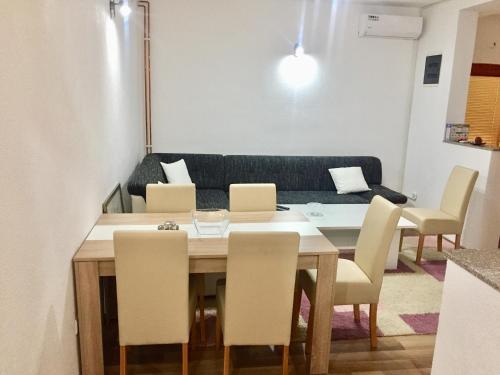 a dining room table with chairs and a couch at Apartman AS in Bihać